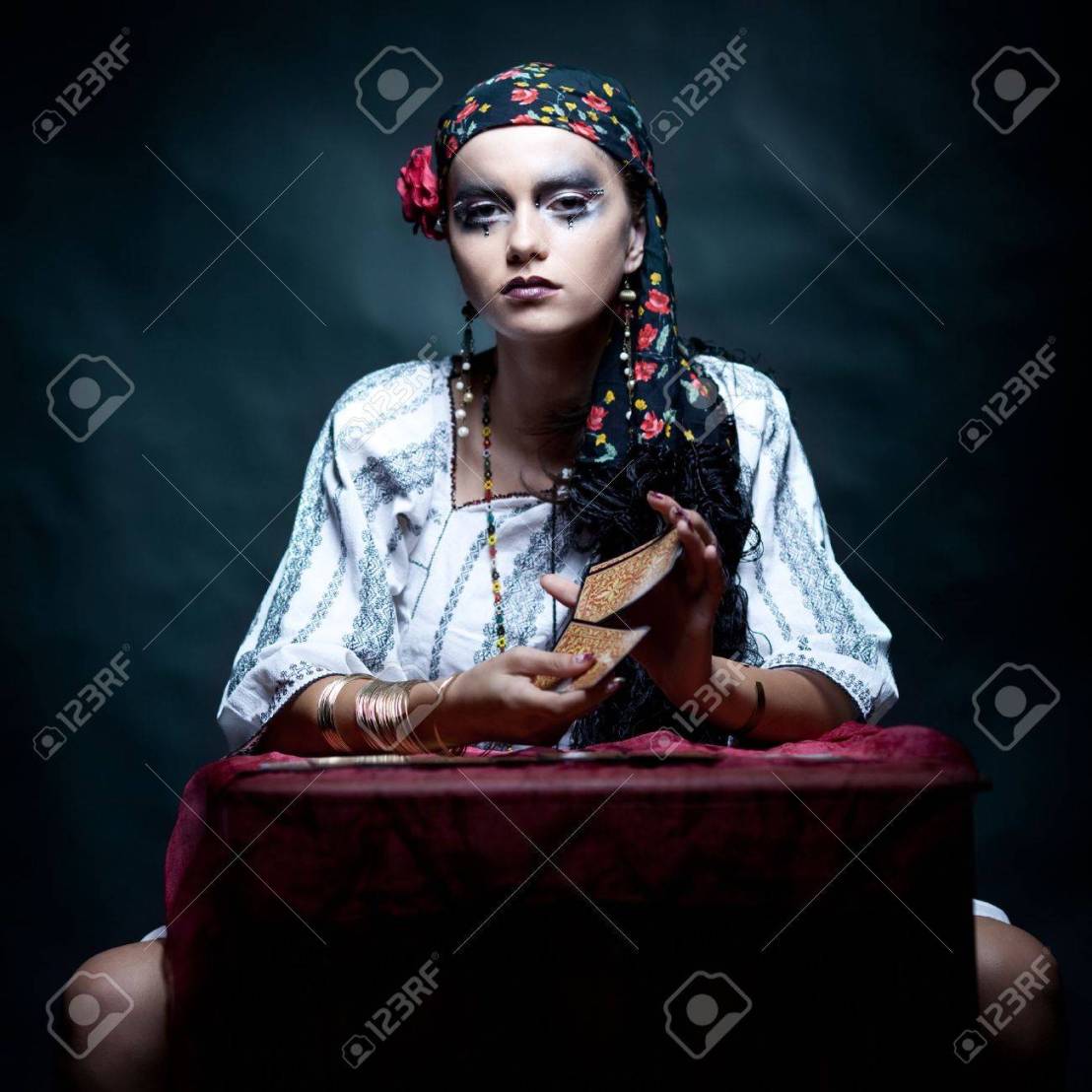 8894649-a-portrait-of-a-gypsy-fortune-teller-sitting-at-a-table-and-mixing-the-tarot-cards-that-she-holds-in